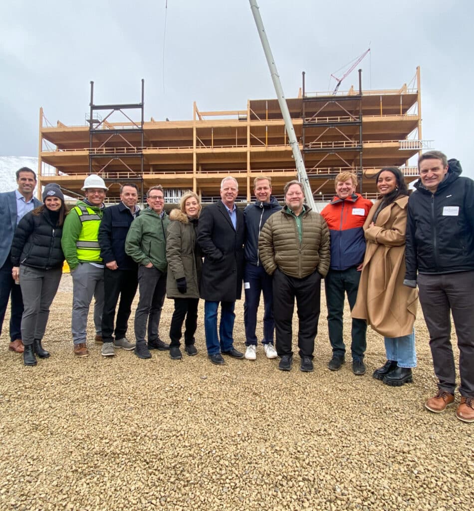 Group of people at construction site, standing in winter coats smiling for photo