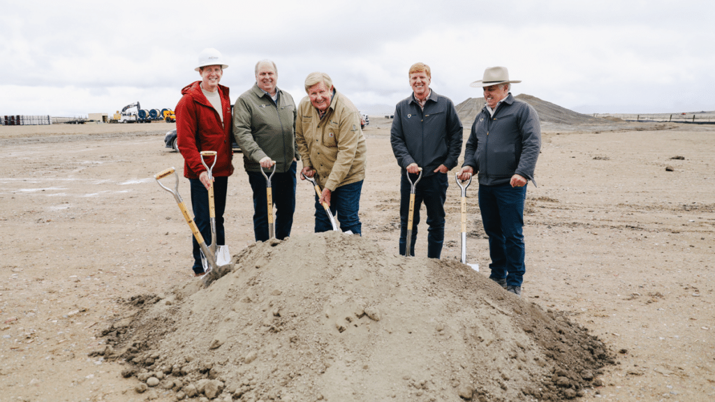 people in a row with shovels commemorating breaking ground at a construction site